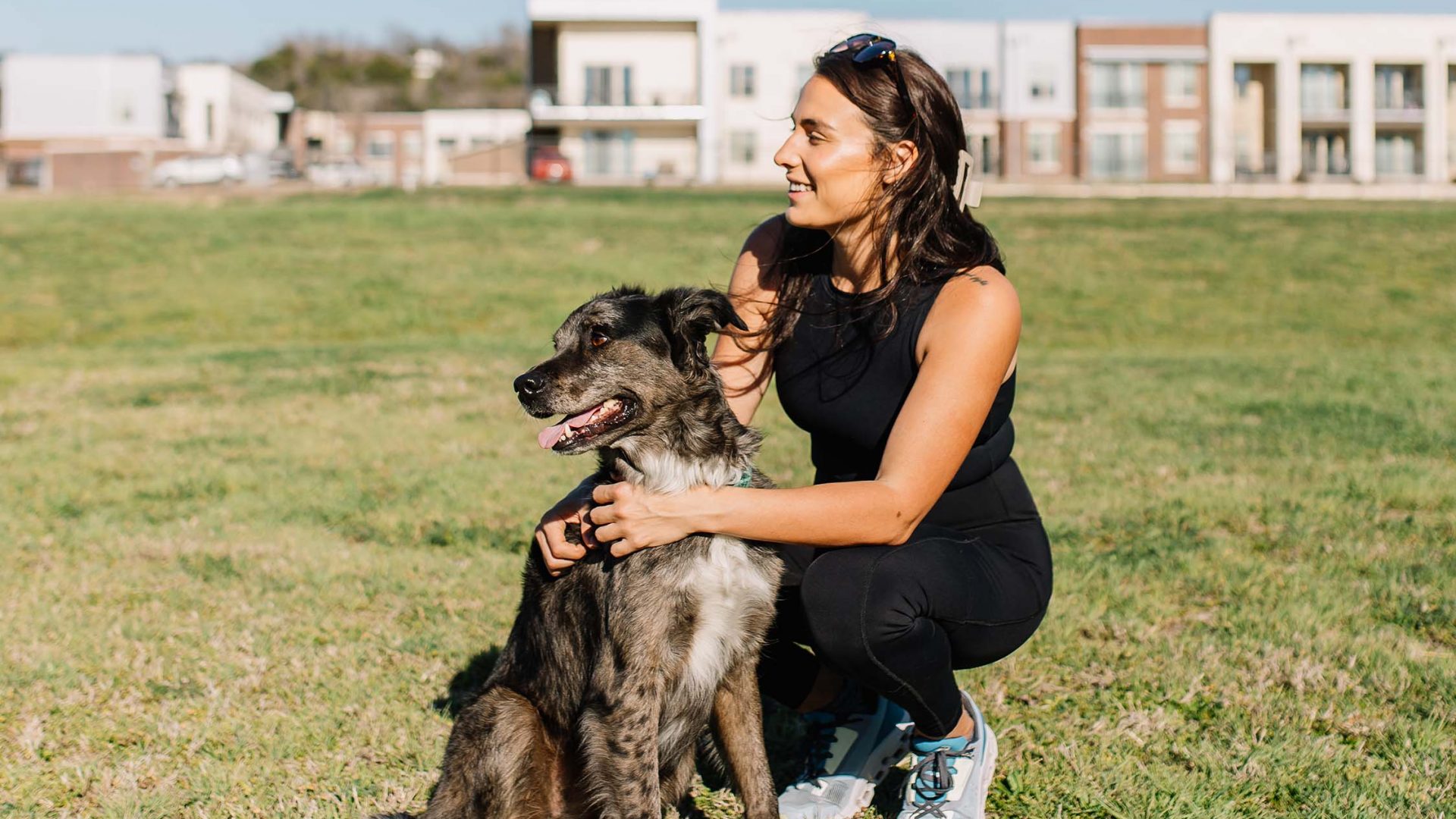 a woman kneeling down with her dog in the green space at The Gates at Meadow Place