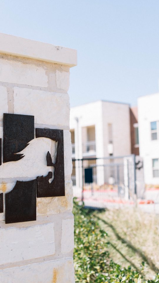 a horse statue on a sign in front of a building at The Gates at Meadow Place