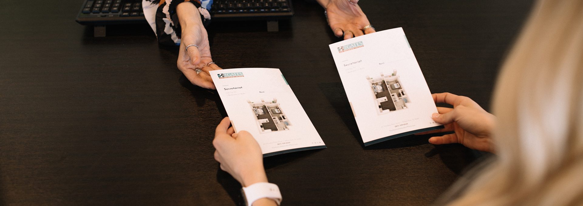 two women sitting at a table with apartment brochures at The Gates at Meadow Place