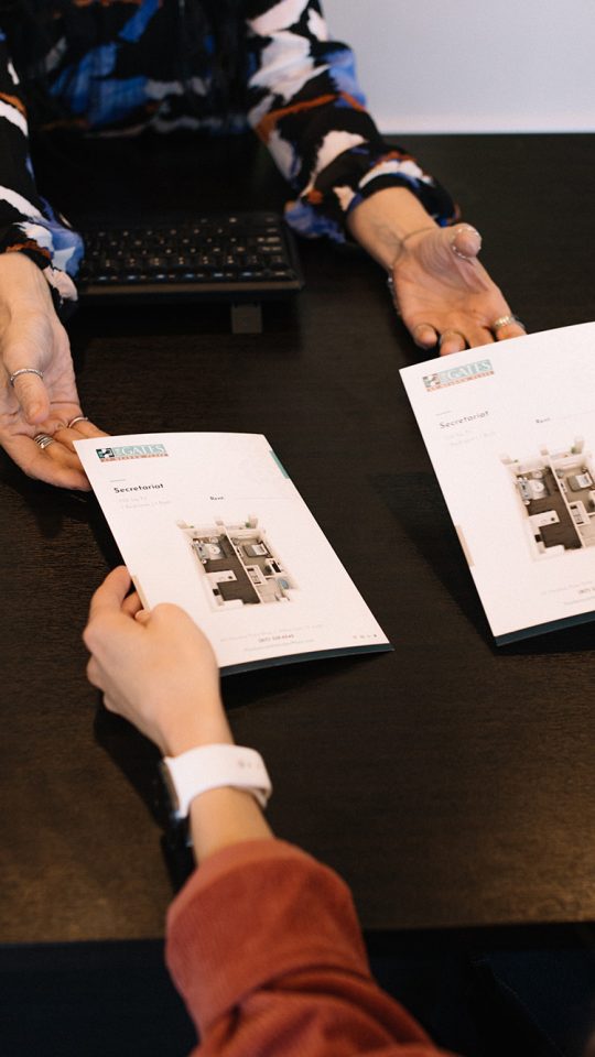 two women sitting at a table with apartment brochures at The Gates at Meadow Place