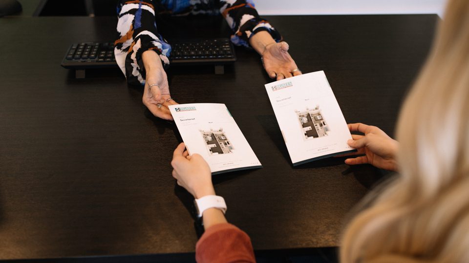 two women sitting at a table with apartment brochures at The Gates at Meadow Place