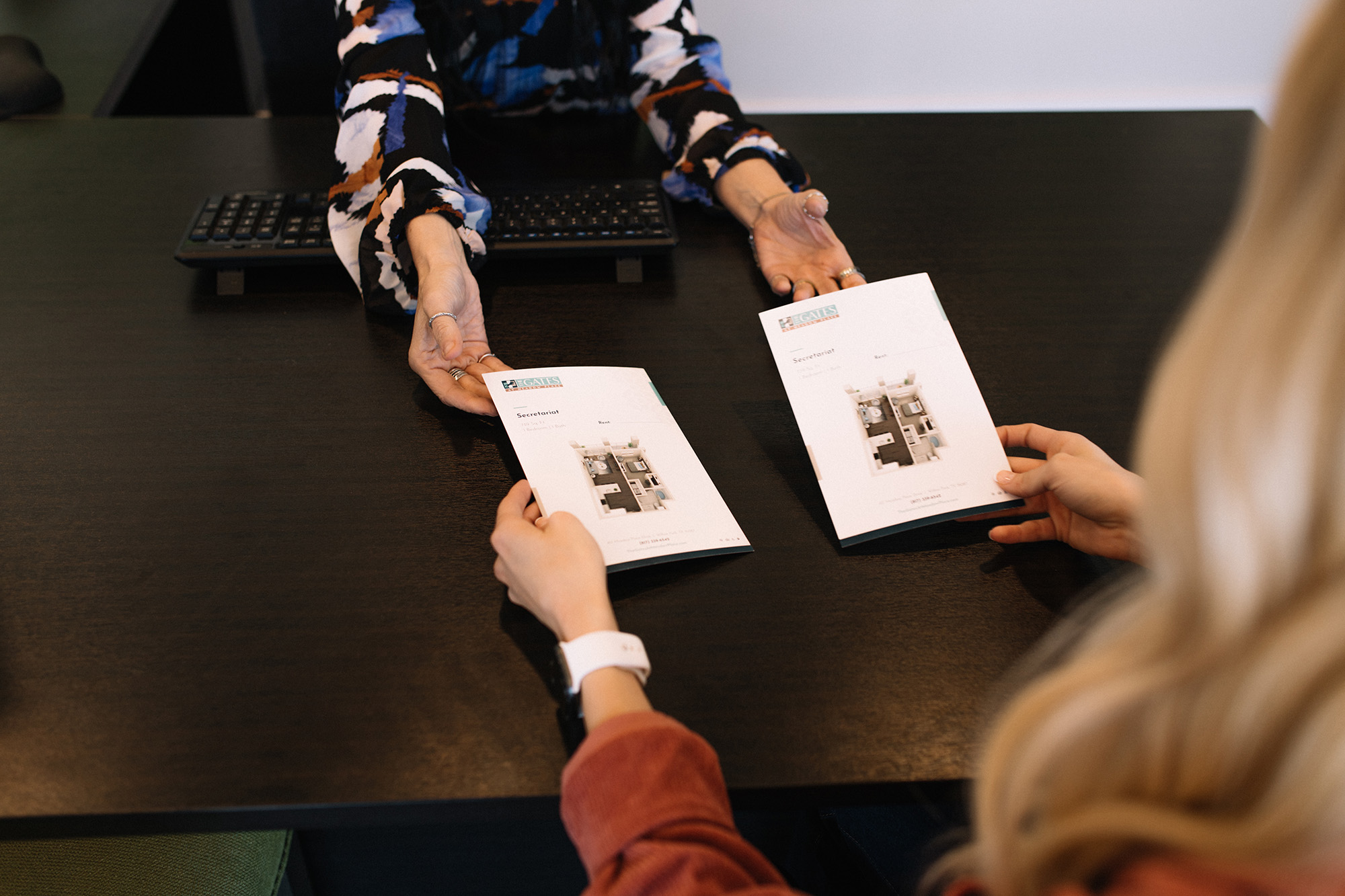 two women sitting at a table with apartment brochures at The Gates at Meadow Place