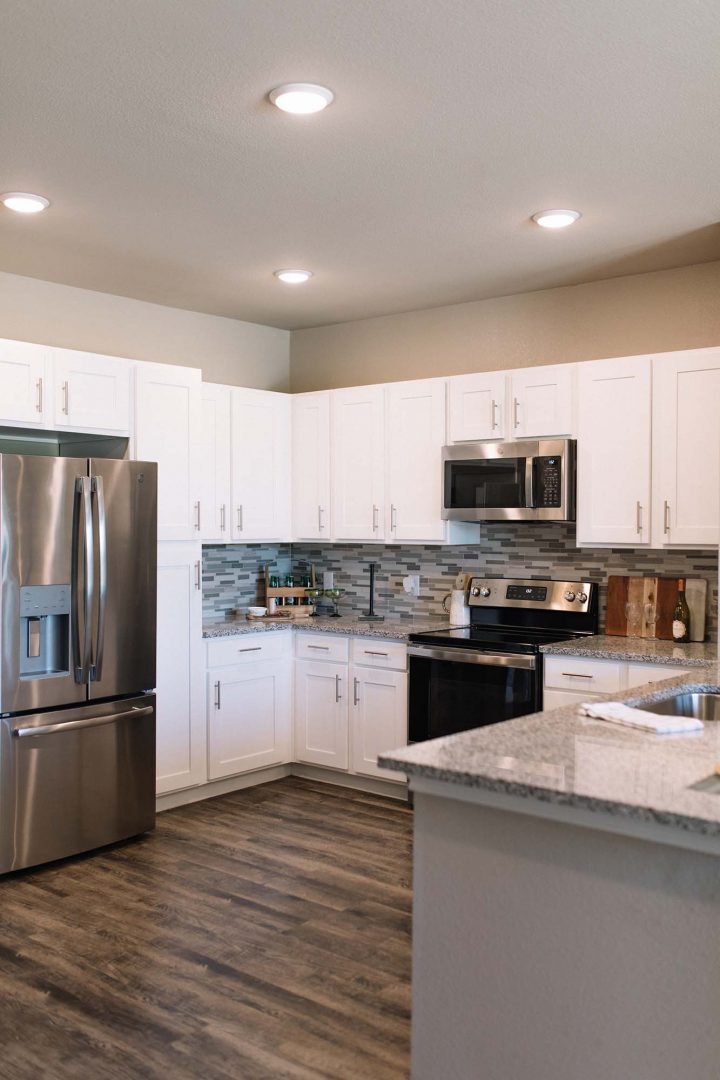 a kitchen with stainless steel appliances and white cabinets at The Gates at Meadow Place