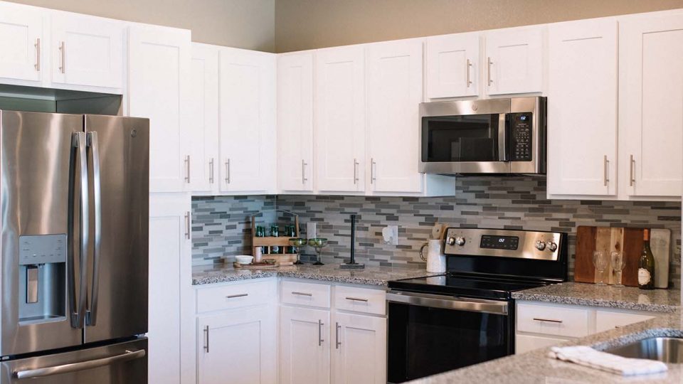 a kitchen with stainless steel appliances and white cabinets at The Gates at Meadow Place