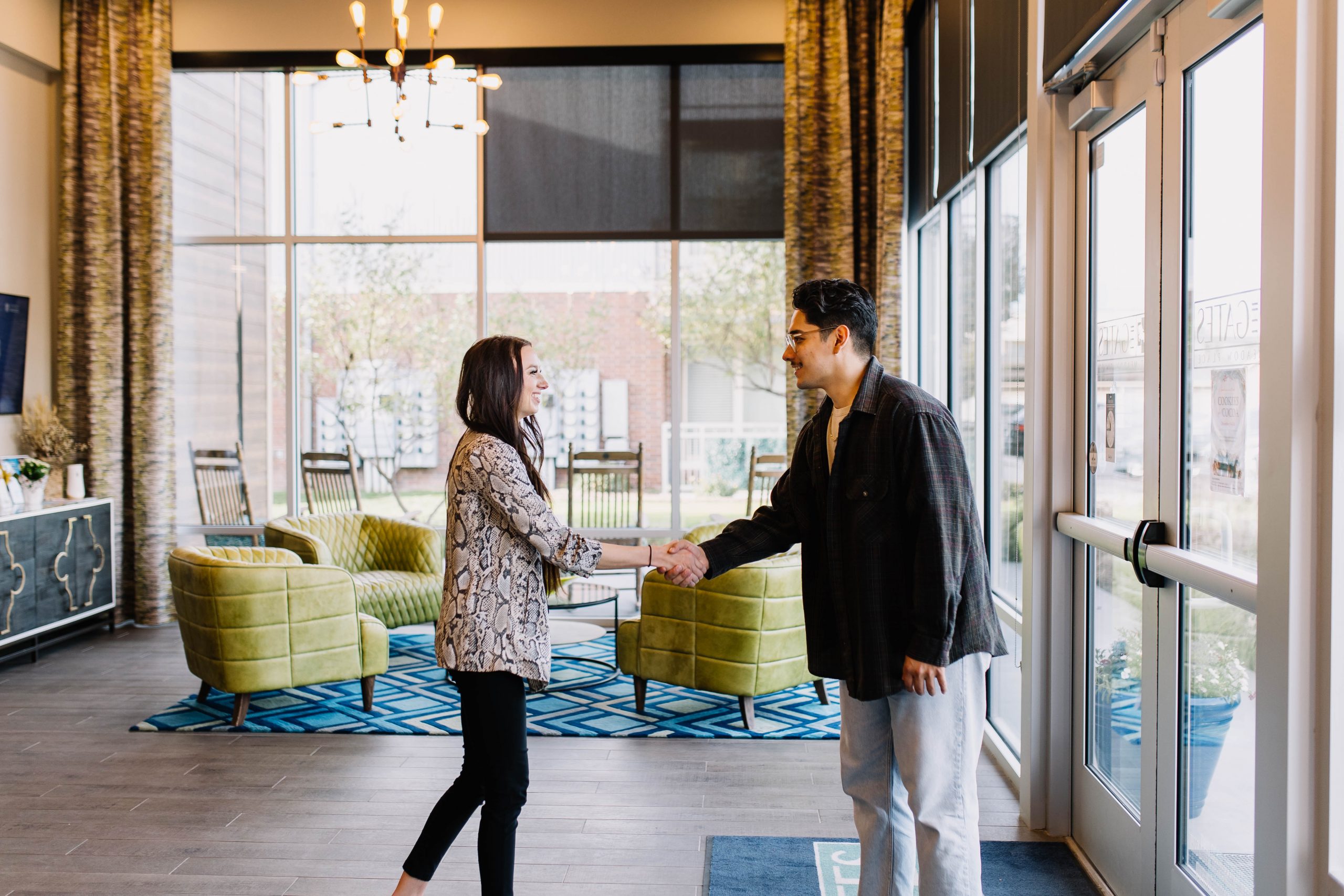 two people shaking hands in front of a large window at The Gates at Meadow Place